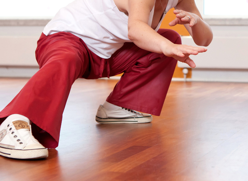 Frau in roter Hose und wei�em Top bei anstrengender Tai Chi-�bung